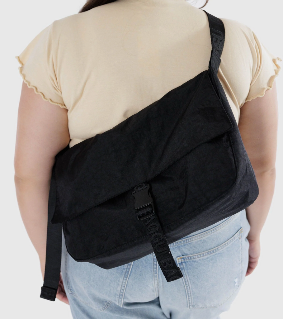 The Baggu Black Messenger bag being worn as a cross body and on the back. 
