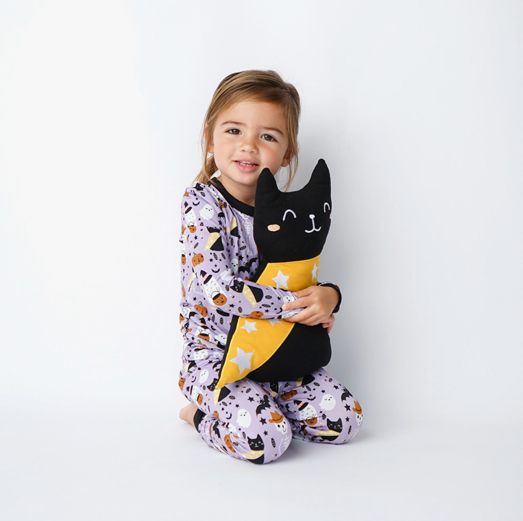 Black Cat Bamboo plush being held by a girl in pajajams.