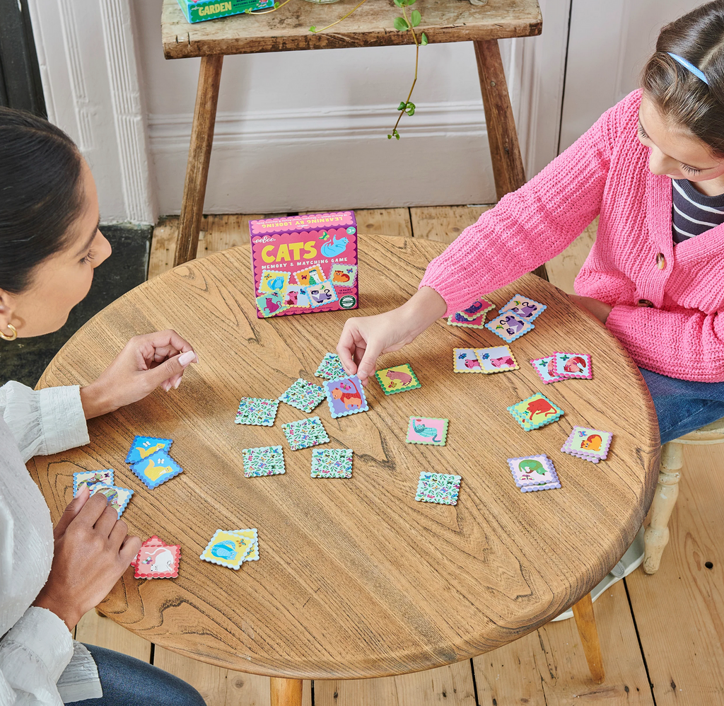 Two people sitting at a table playing the Cats Memory and Matching game.