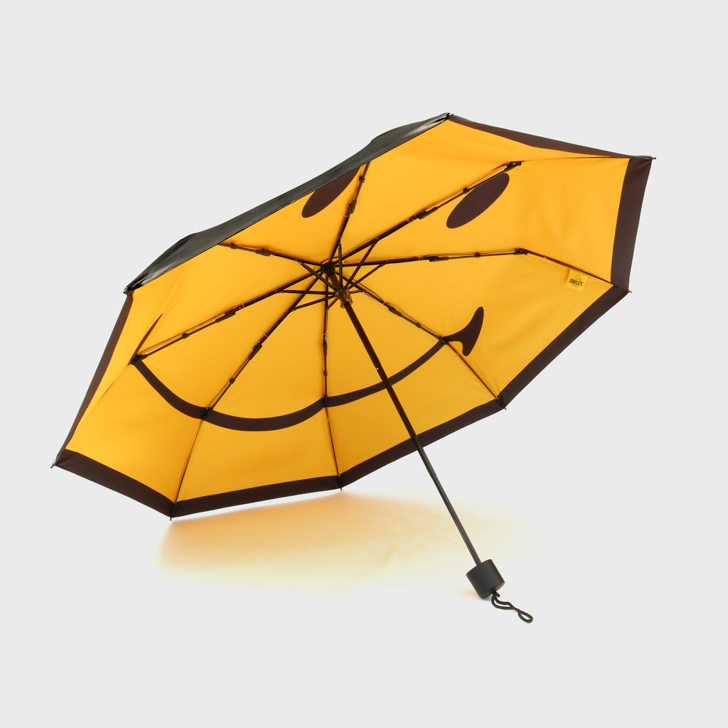 Smiley umbrella opened to show the underside of the umbrella with a yellow smiley face and black handle. 