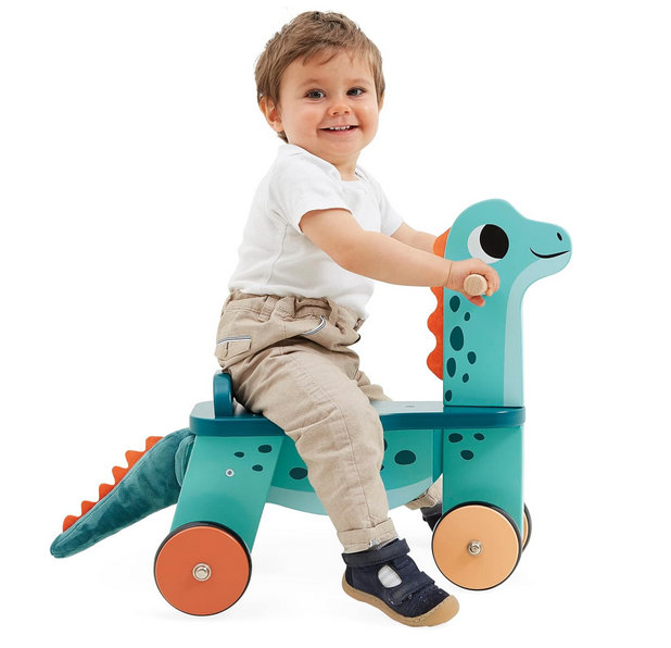 Side view of the Dinosaur Ride On with a toddler sitting on it. 