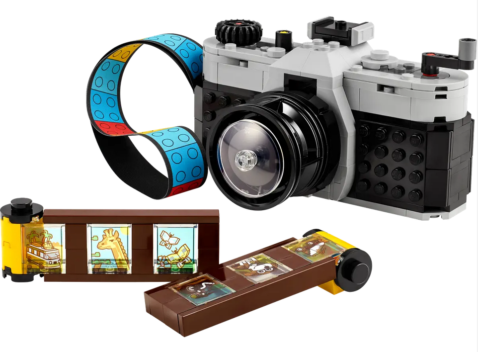 Brick built retro camera with colorful strap and film rolls. 