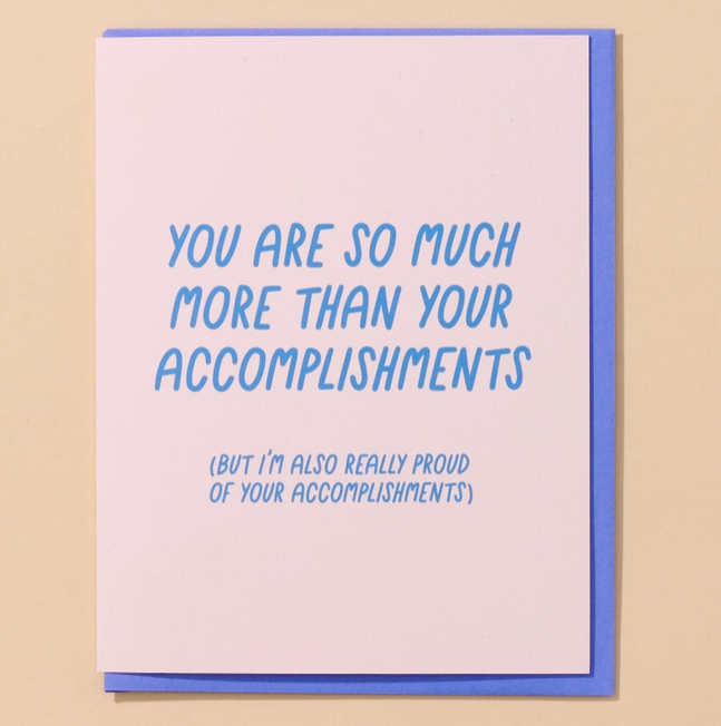 Light pink greeting card with bright blue lettering that reads " You Are So Much More Than Your Accomplishments (But I'm Also Really Proud Of Your Accomplishments)