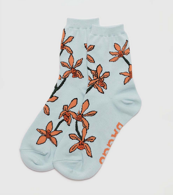 Pair of crew socks that are light blue with orange orchid flowers on them. 
