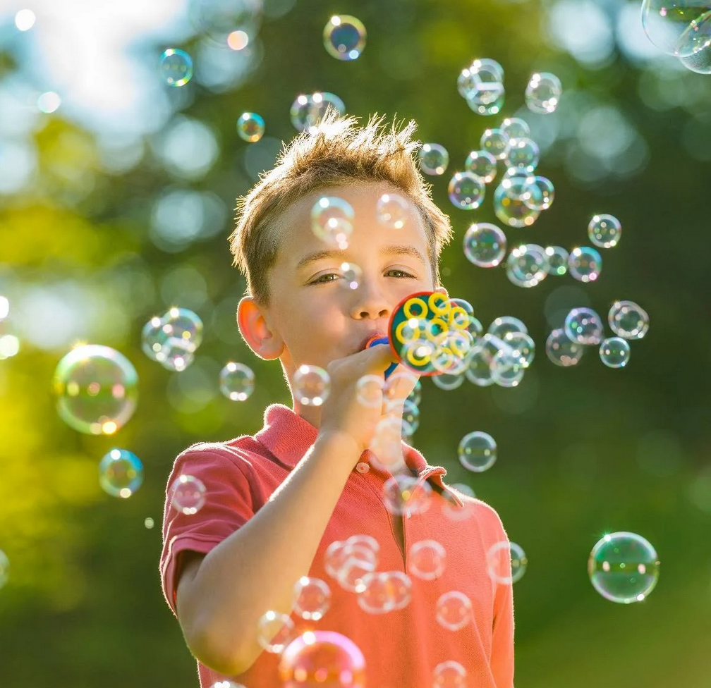 A small boy blowing lots and lots of bubbles with the bubble trumpet.
