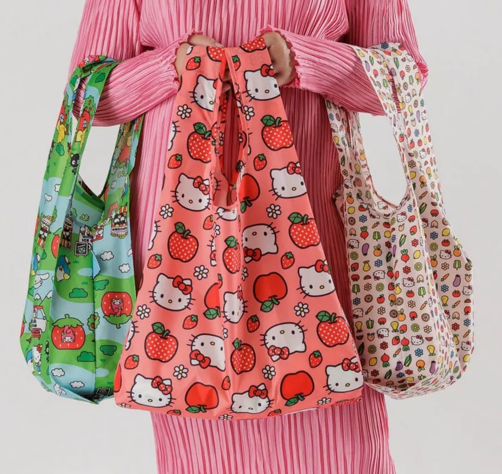 Each of the three Hello Kitty standard Baggu bags being carried by the handles. 