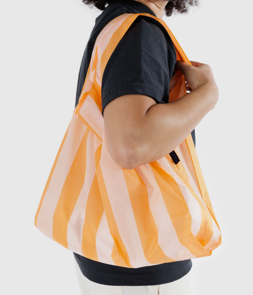 Tangerine Wide Stripe standard Baggu being carried on a shoulder.