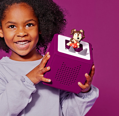 A young child holding the purple Toniebox.