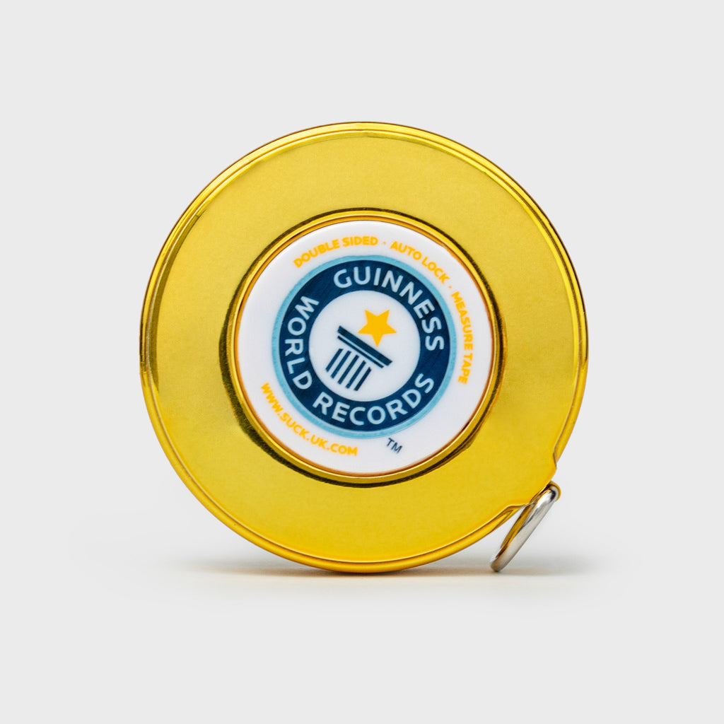 Tape measure housed in gold, round case with white label that reads " Guinness World Records" in blue. 