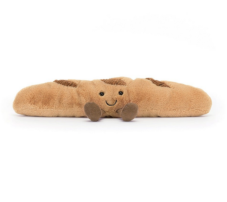 The plush baguette sitting and facing forward. With a sweet smile and his brown feet out in front of him, he looks good enough to eat! 