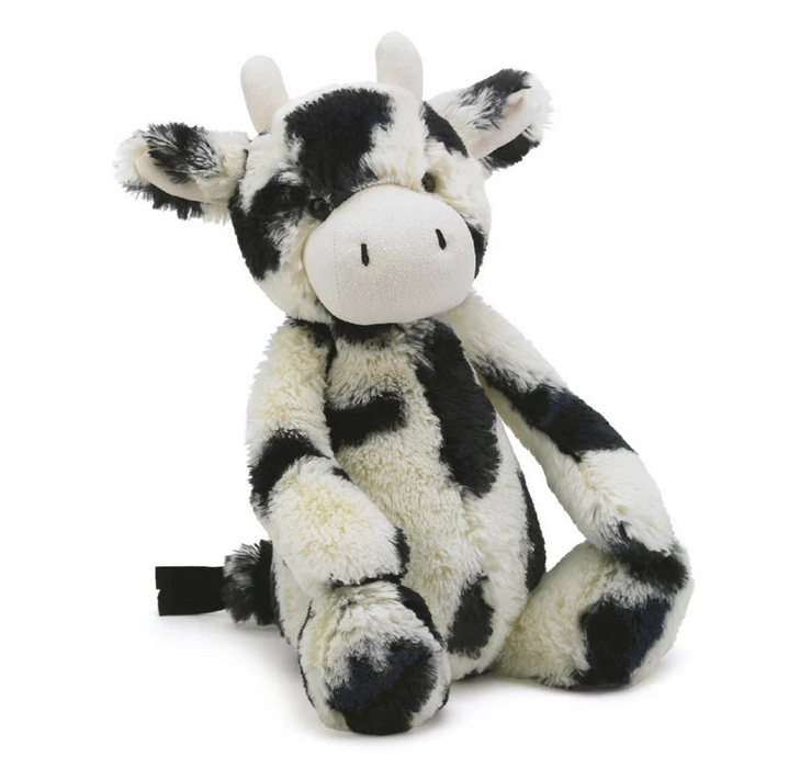 Black and white plush cow with white horns. 