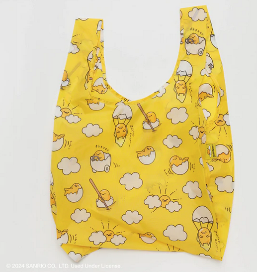 Standard Baggu Bag with Gudetama print that is bright yellow and Gudetama doing various activities such as driving an egg car, rowing an egg boat, parachuting with an eggand just laying in an egg. 