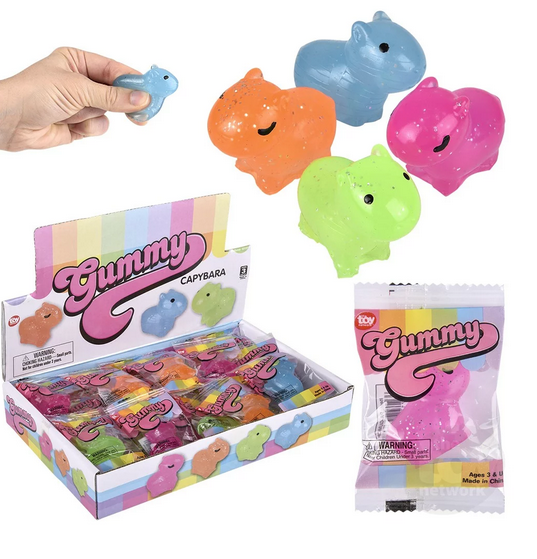 Picture of the Gummy Capybara in a display box, a close up of one in the plastic package, and the four colors available. Orange, green, pink and blue. 