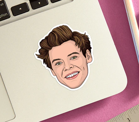 Die cut vinyl sticker of Harry Styles face. The sticker is stuck on the bottom corner of a laptop.