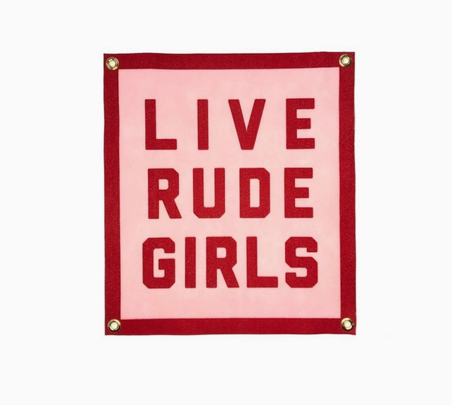 Square pink felt banner with red border and lettering that reads "Live rude girls"