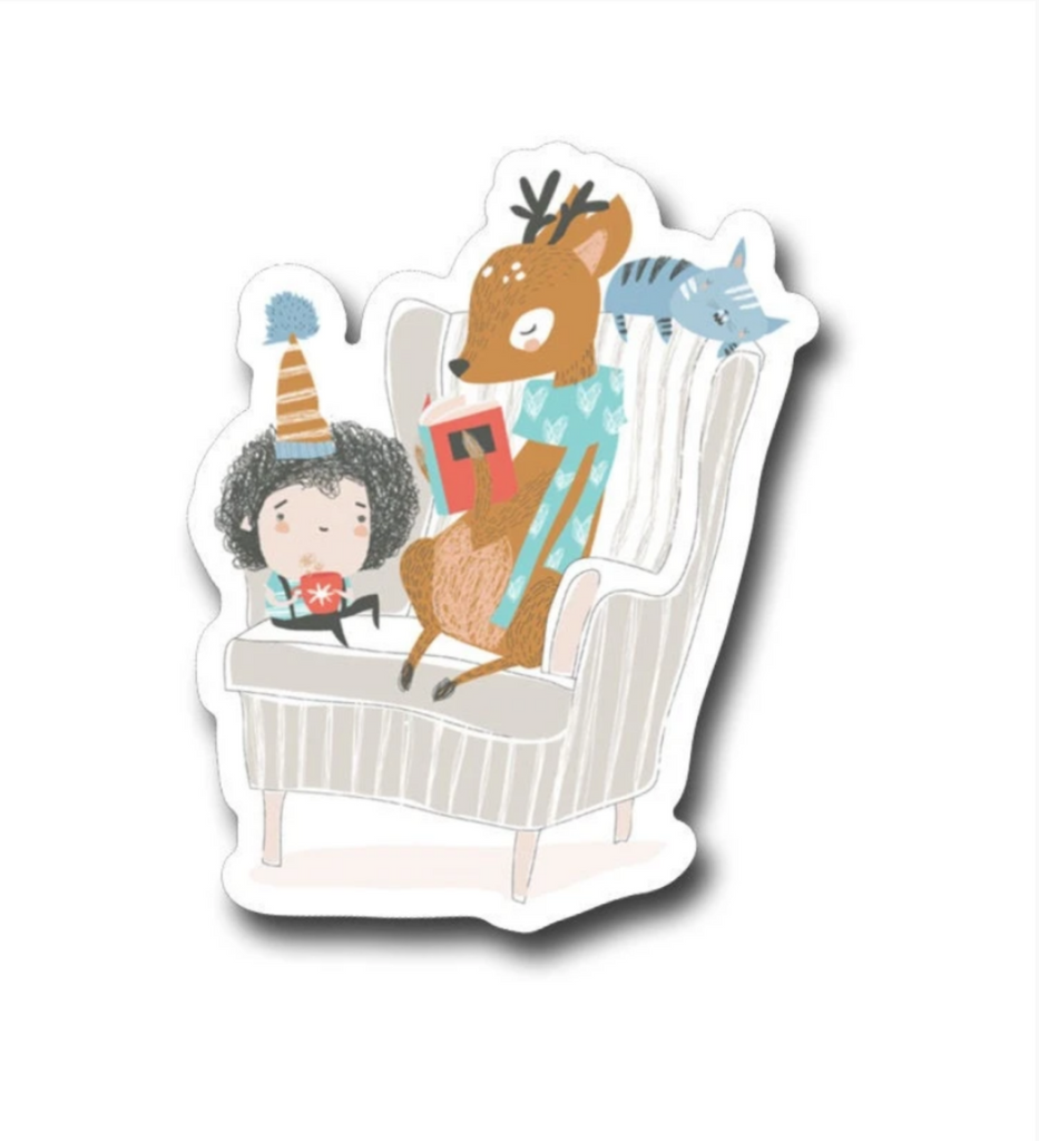 Diecut sticker of a child with a hat holding a mug, a deer in a blue heart sweater reading a book, and a small blue cat laying across the back of an armchair.