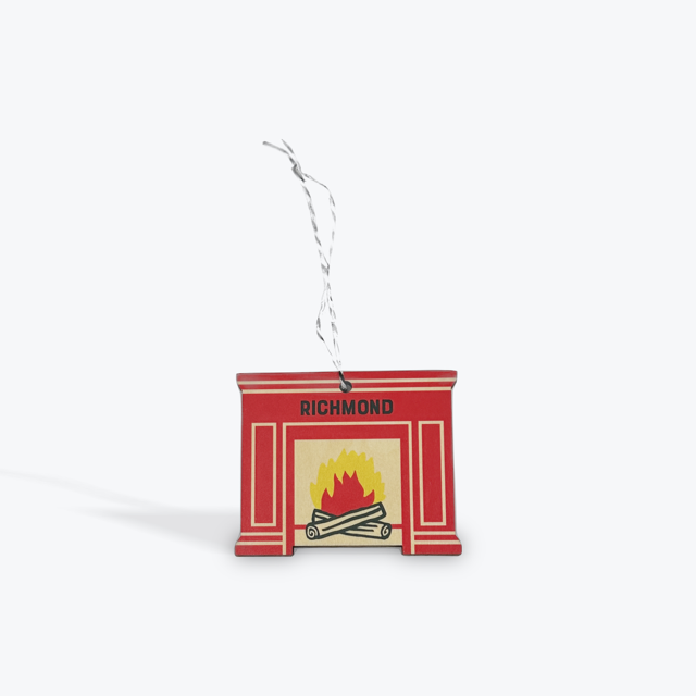 Red fireplace with fire burning inside wood ornament with Richmond printed on it. 