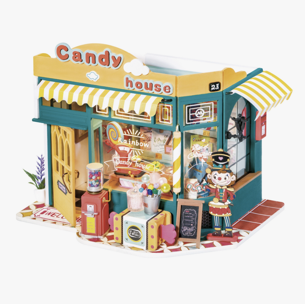 Rainbow Candy House DIY Miniature House kit, Kit is a brightly colored candy shop with yellow and white striped awnings, candy out front, and interior shelves full of treats.