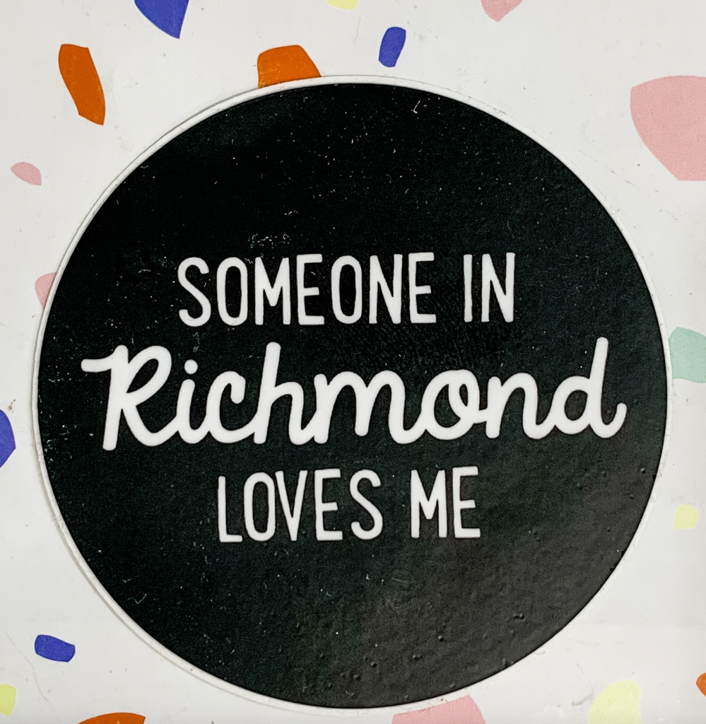 Round black sticker that reads Someone In Richmond Loves Me in white text.