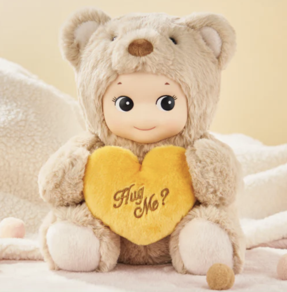 Sonny Angel Brown Cuddly Bear plush figure holding a yellow plush heart that says "Hug Me?" in brown.