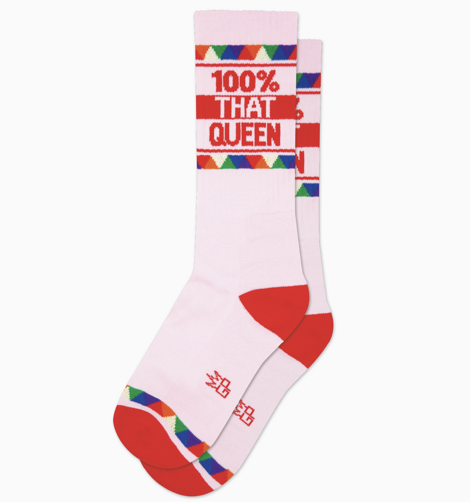 Light pink tube socks with red and multi colored stripes that read "100% That Queen" in red letters. 