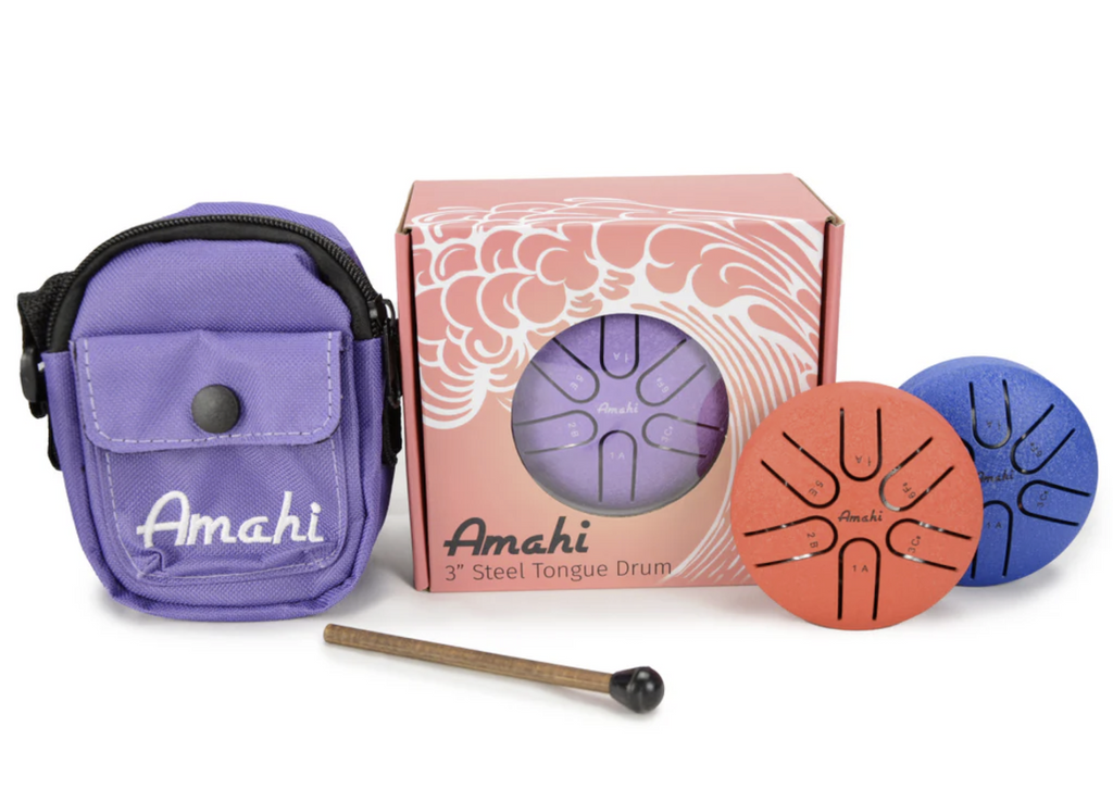 Three inch steel drums by Amahi. A purple drum is in it's box with a clear window that enables the front of the drum and color to be seen. There are a red and blue drum to the side of the box and on the other side is a purple carry bag for the drum and a mallet. 
