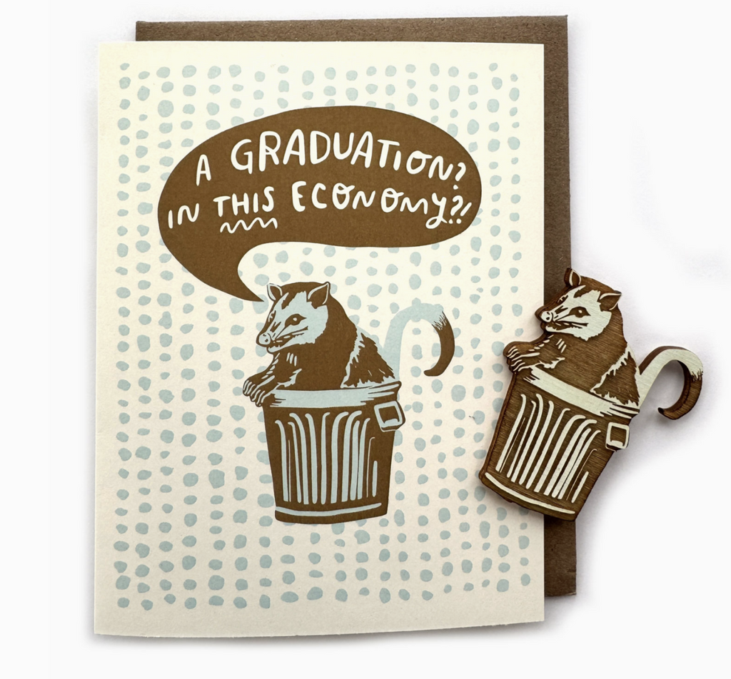 Greeting card with blue dot repeating pattern and illustration of a possum in a trashcan. A magnet of the possum in a trashcan is off to the side.