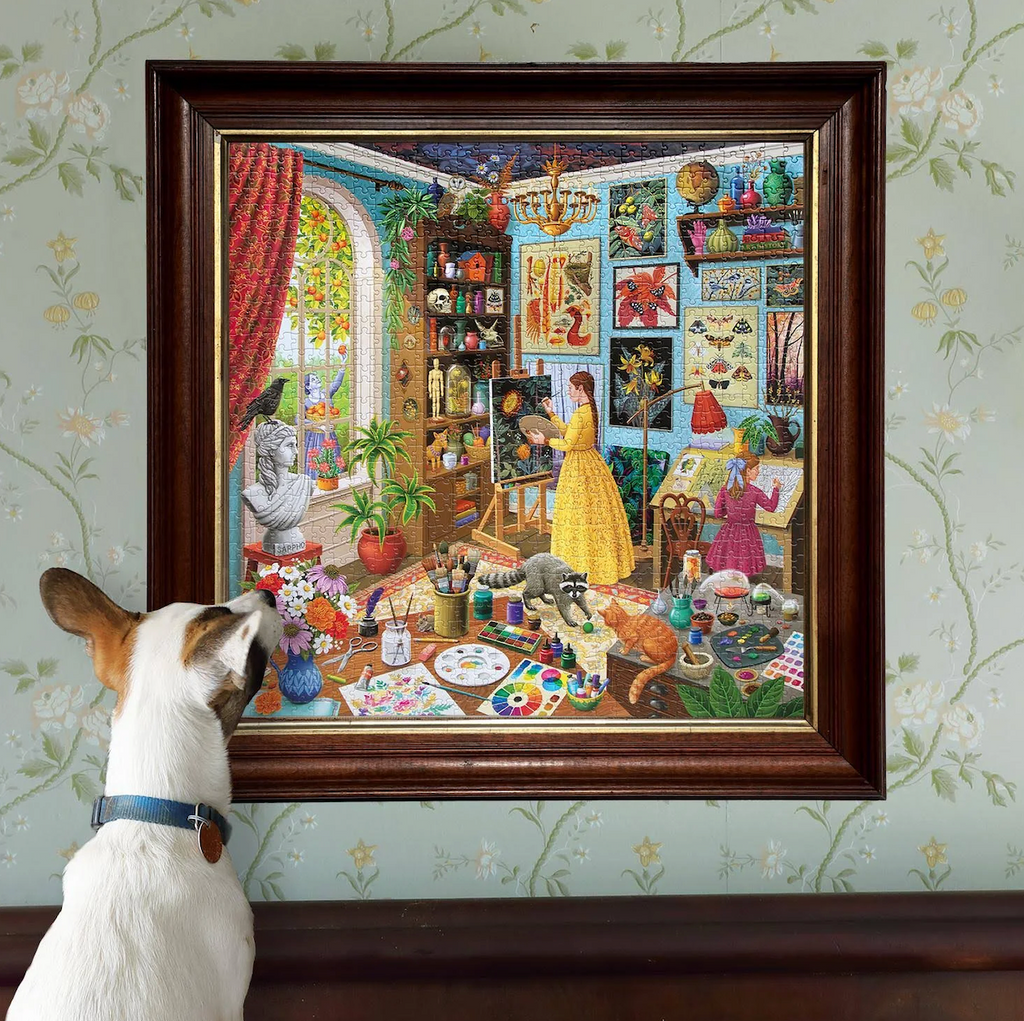 A framed puzzle depicting the alchemist's studio with cats, shelves full of atifacts, an tools, with a white and brown dog looking up at the puzzle.