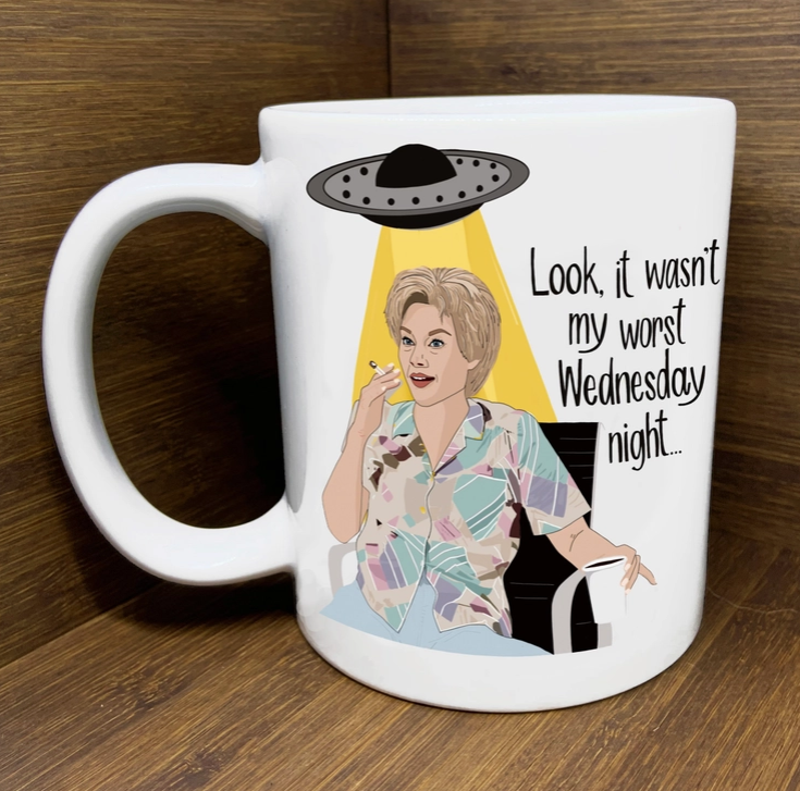 White ceramic mug with illustration of Kate McKinnon's character from SNL that repeatedly gets abducted by aliens with quote that reads " Look, it wasn't my worst Wednesday night...."