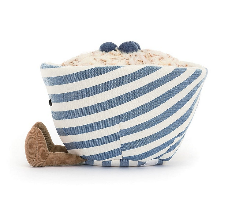 Side view of the blue and white striped plush bowl of golden brown oatmeal with bluberries on top. 