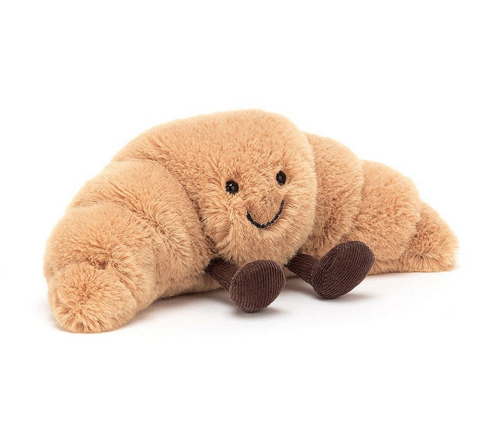 Tan plush croissant with brown fabric feet on a white background.