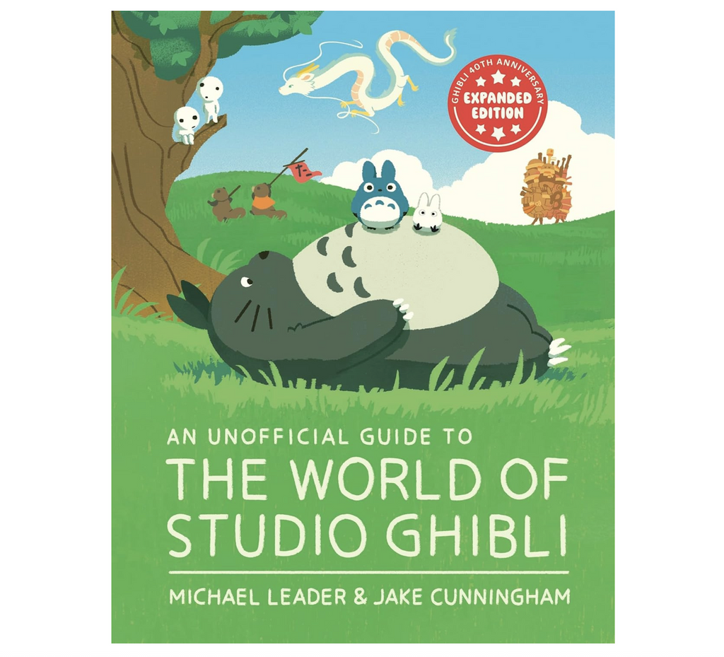 Illustrated cover of "An Unofficial Guide To The World of Studio Ghibli" that shows Totoro lying on his back in a green field with other creatures from Studio Ghibli surrounding him.