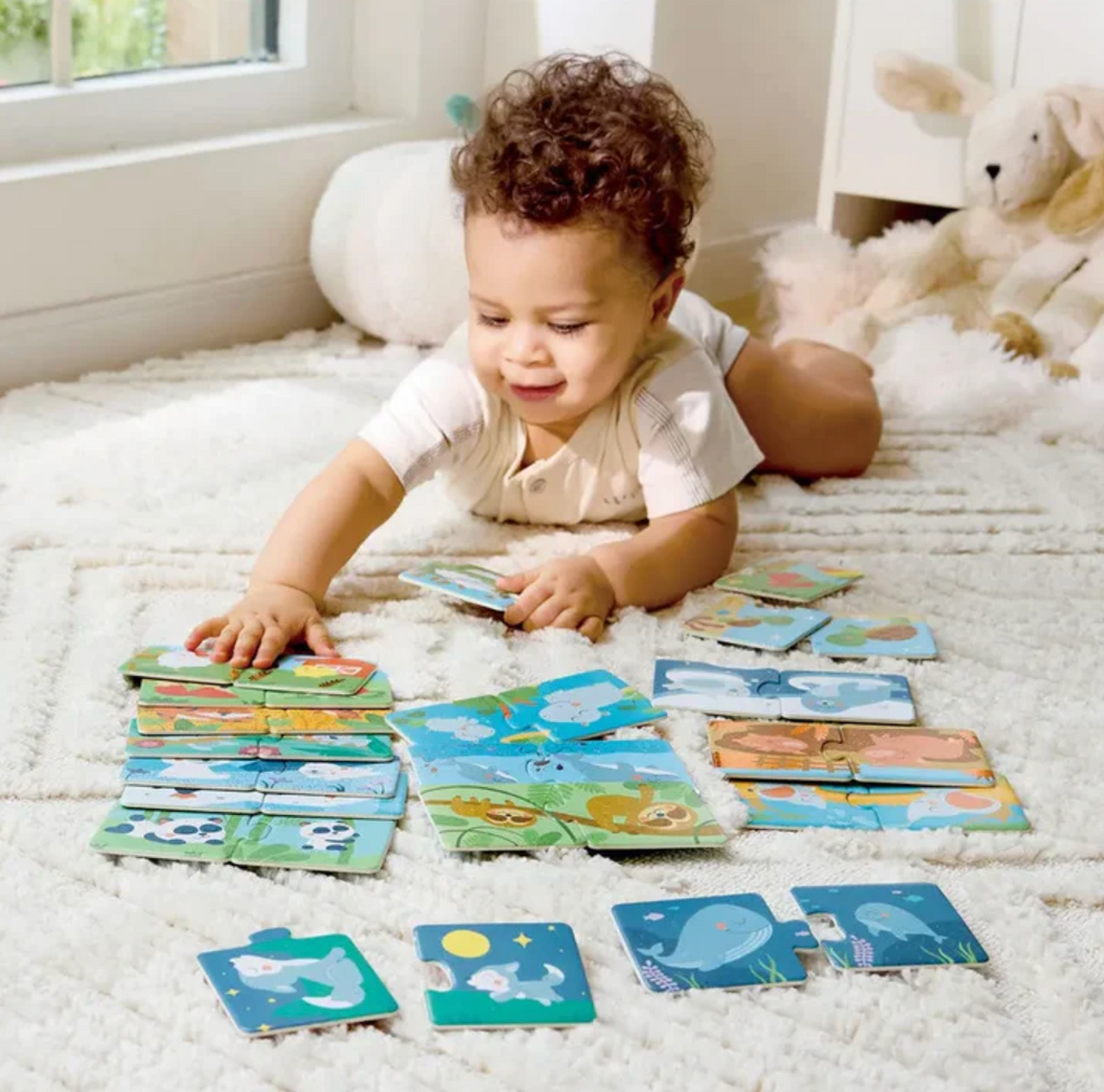 Child on a white rug playing with the animal pair puzzles pieces.