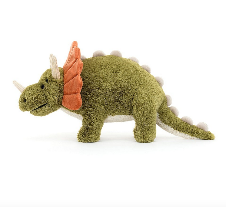 Archie the plush triceratops from the side, with green body, orange crill, and cream colored horns and spikes down his back. 