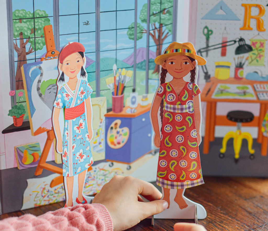 Child playing with dressed Artist & Musician standing paper dolls in front of included playscene.