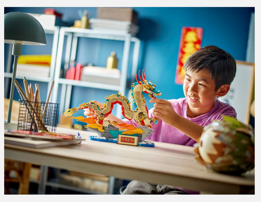 Young boy sitting at  a tbale in his room playing with the Auspicious Dragon.