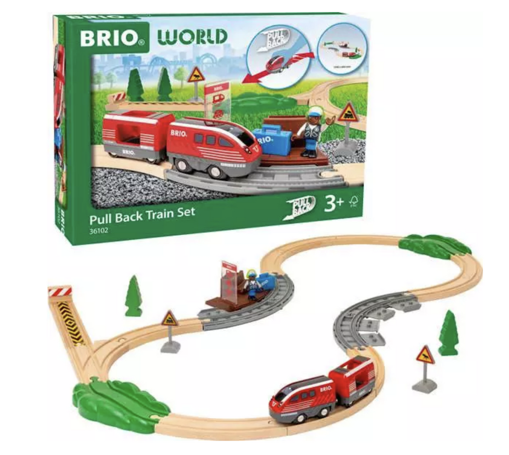 Wooden train tracks pieced together to form a circular track that the red train and car travel on. The box that the Pull Back Train Set comes packaged in is standing in the brackground. 