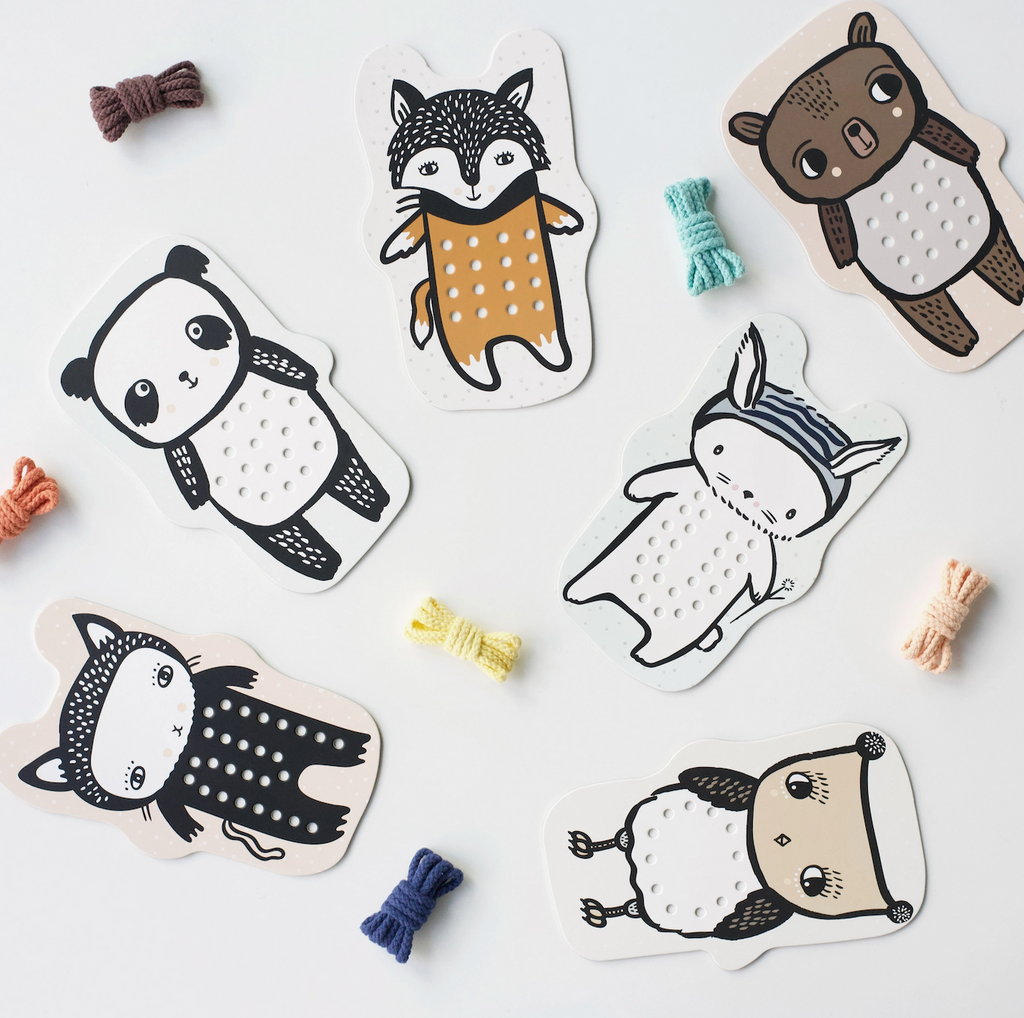 Set of six baby animal lacing cards with the colorful string placed around the cards on the table. 