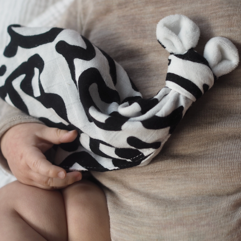 Closeup of a baby snuggling with a black and white baby lovey.