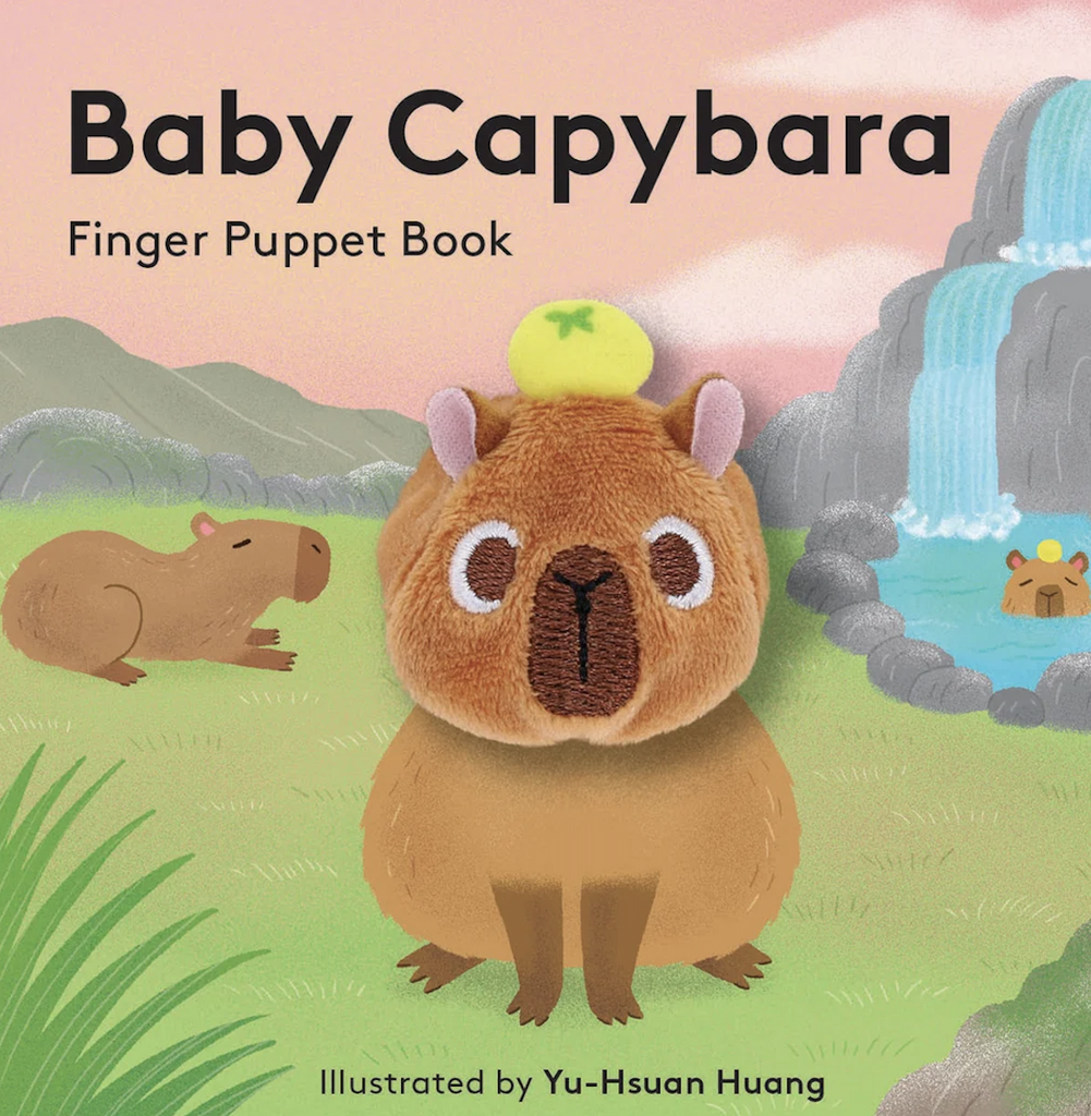 Cover of the Baby Capybara Finger Puppet Book with an illustrated cover featuring capybaras in a grassy meadow by a waterfall with the main capybara as a finger puppet that is the main character on every page throughout the story. 