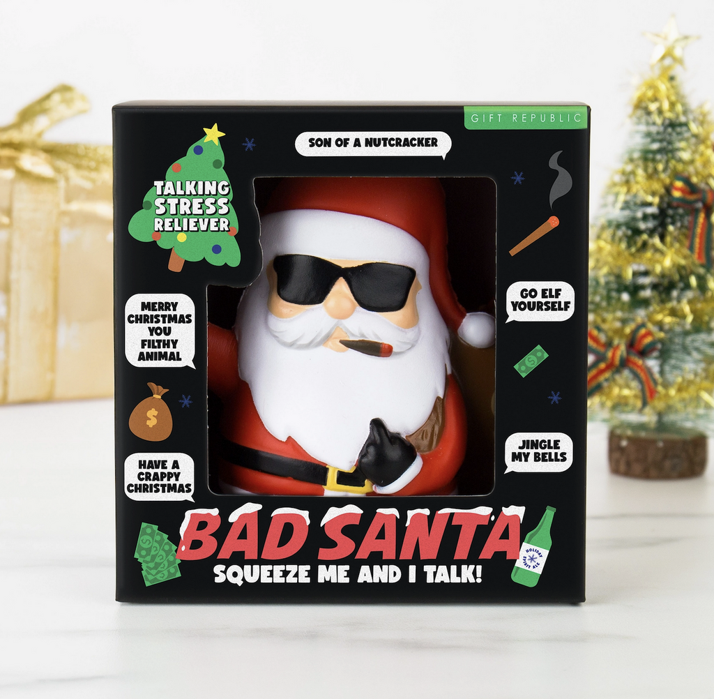 Bad Santa Stress toy wearing sunglasses and smoking a cigar packaged in an open box with word bubbles of the cheeky phrases Bad Santa says. 