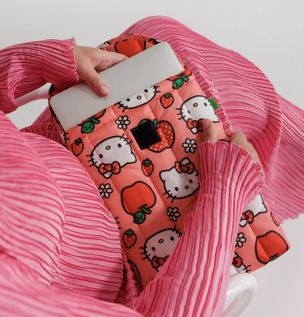 Hello Kitty Apple print puffy laptop sleeve holding a laptop in someones lap. 