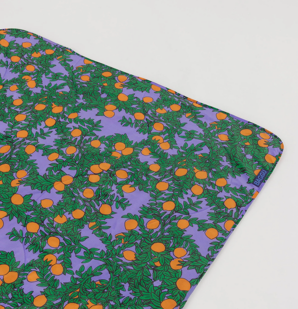 Orange tree print on periwinkle background laid out flat. 