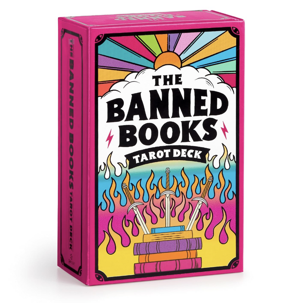 The Banned Books Tarot Card Deck cover box with a hot pink background, rainbow colors coming off the sun and three swords plunged into a stack of books with flames coming off them  on the front. 
