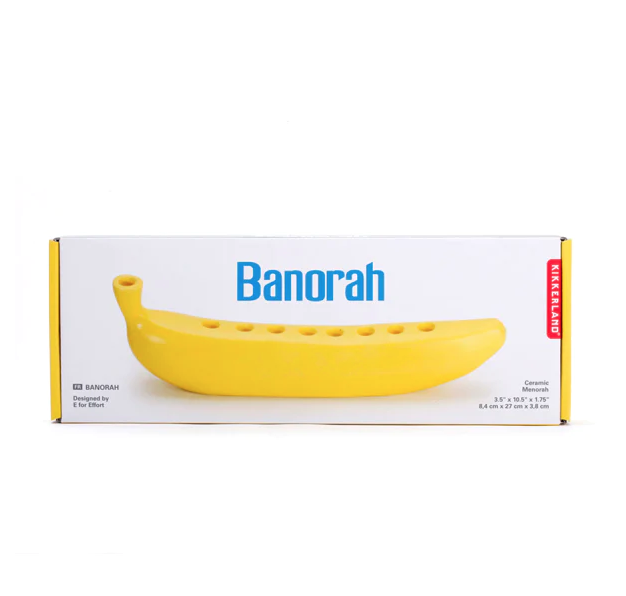 White box with a picture of a yellow ceramic menorah in the shape of a banana with blue lettering. 