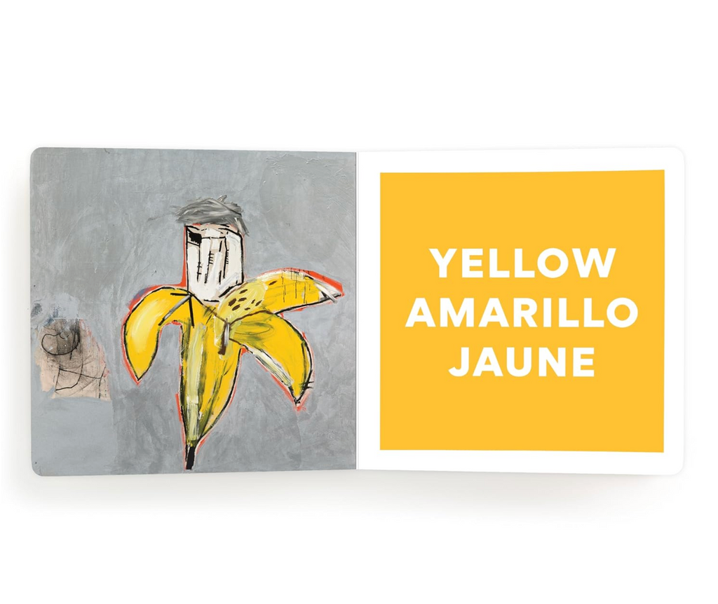 Interior page from the Basquiat Colors Board Book depicting a yellow banana on a grey background. The opposite page is yellow with the word written in English, Spanish and French in white letters.  