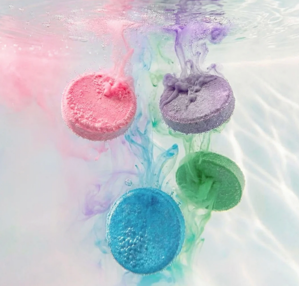 Pink, purple, green and blue tablets dissolving in water. 