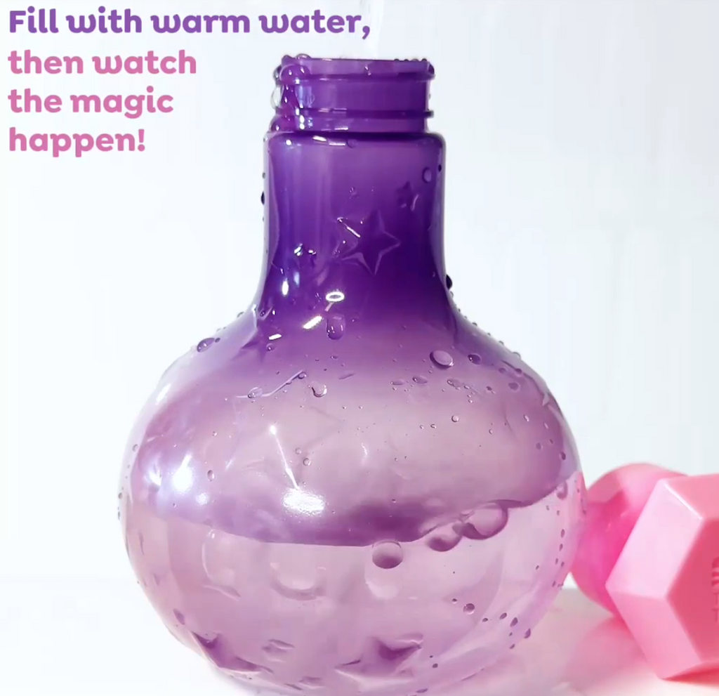 A close up picture of the Bath Magic Color Change Potion Bottle partially filled with warm water and in the process of changing form purple to pink. 