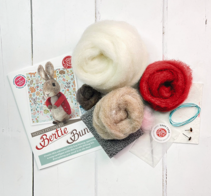 Red, white, and tan wool, needles, floss and the instruction book for the Bertie Bunny Needle Felting Kit. 