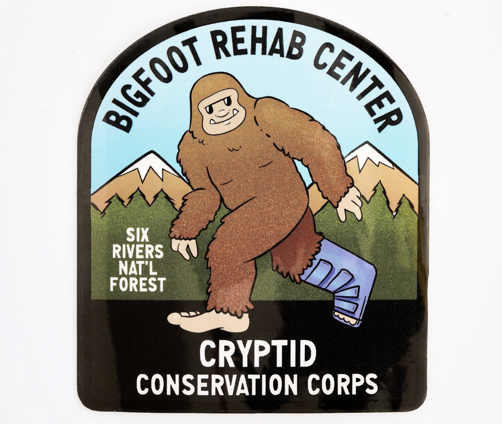 Sticker with illustration of a brown bigfoot walking with his right foot in a boot. The sticker reads "Bigfoot Rehab Center, Cryptid Conservation Corps" 